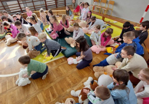 uczniowie ćwiczą masaż serca na pluszowych misiach